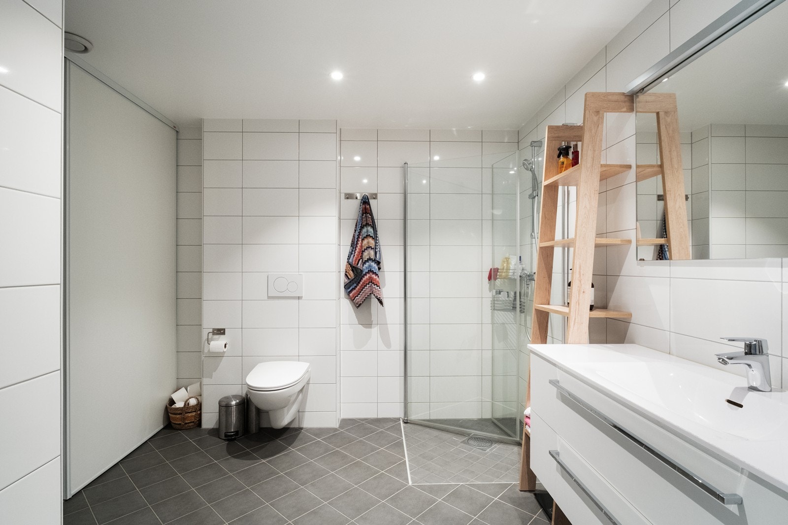 Badet er romslig og utstyrt med vegghengt wc, dusjhjørne med innfellbare glassvegger og heldekkende servant med underskap. Skyvedører til vaskeromsdelen av badet. Galleribilde