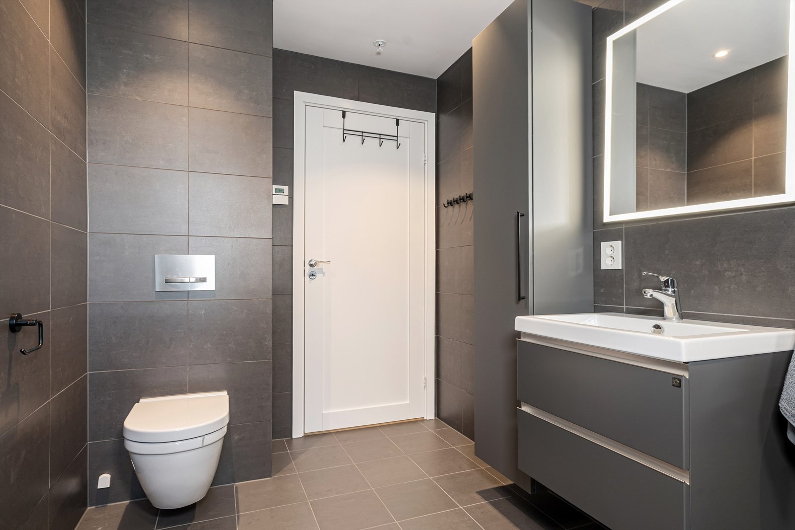 Innredet med dusjhjørne, servant med servantskuffer og skap, samt vegghengt toalett. Galleribilde