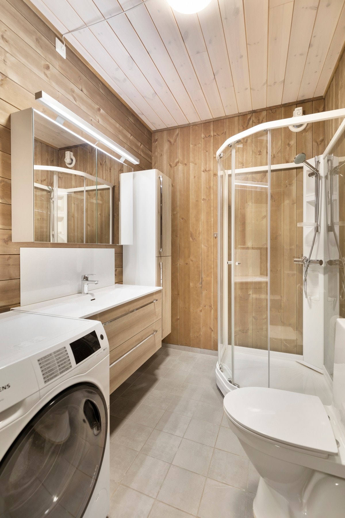 Badet har fliser på gulv og panel på vegger. Rommet er utstyrt med dusjkabinett, toalett, opplegg for vaskemaskin, elektrisk vifte og pen innredning med servant og speilskap/belysning. Rommet har varmekabler i gulv og montert varmtvannsbereder fra 2020. Galleribilde