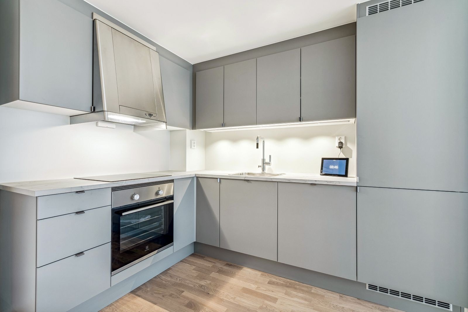 Moderne kjøkken med komfyr, platetopp, kombiskap, oppvaskmaskin og ventilator. Galleribilde