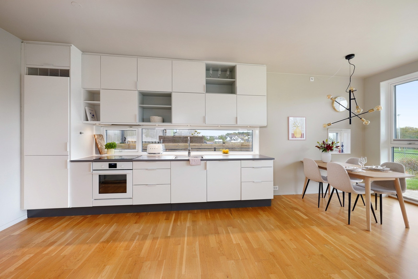 Pent tidløst kjøkken med integrerte hvitevarer som stekeovn, platetopp, oppvaskmaskin og kjøleskap Galleribilde