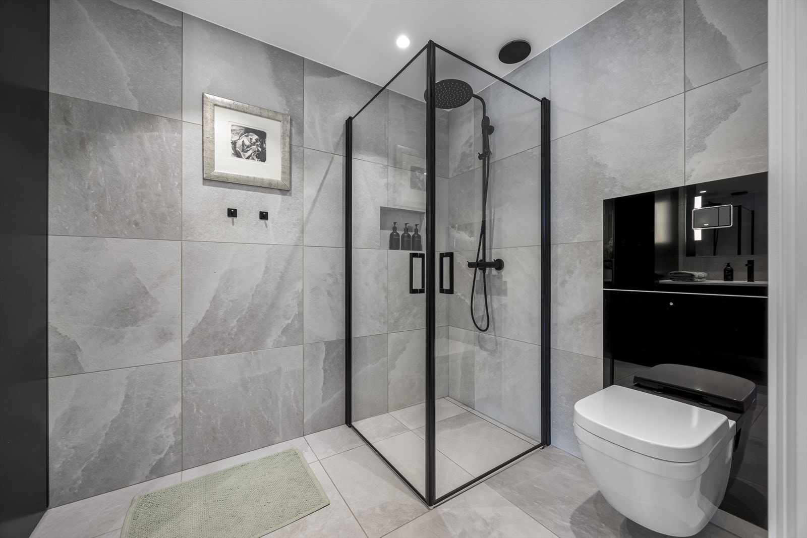 Begge bad er helfliset med lekkert design og påkostede løsninger, store 60 x 60 fliser, vegghengt toalett, servantinnredninger og dusjhjørne med armaturer i sort design. Galleribilde