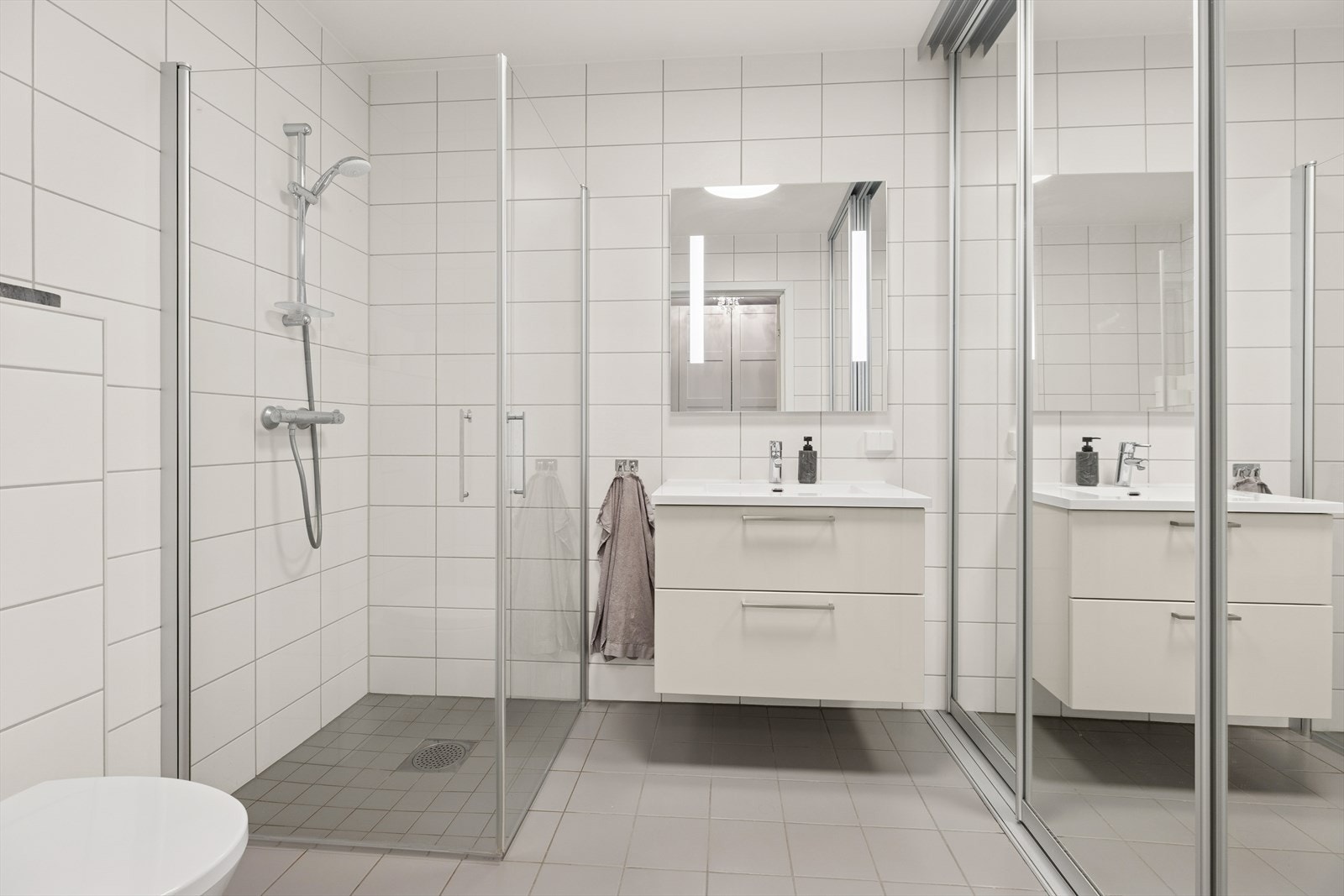 Badet i 1. etasje fungerer som kombinert bad og vaskerom. Flislagte vegger og gulv med elektriske varmekabler gir en komfortabel opplevelse. Galleribilde