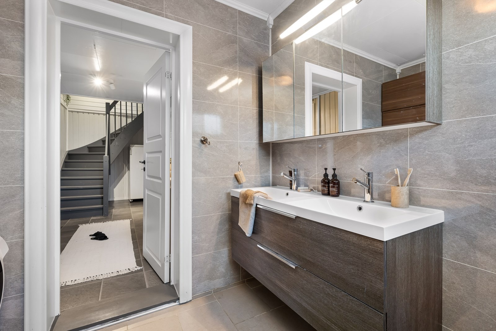 Innredet med toalett, dusjhjørne, opplegg for vaskemaskin, veggskap og servant med innredning. Galleribilde