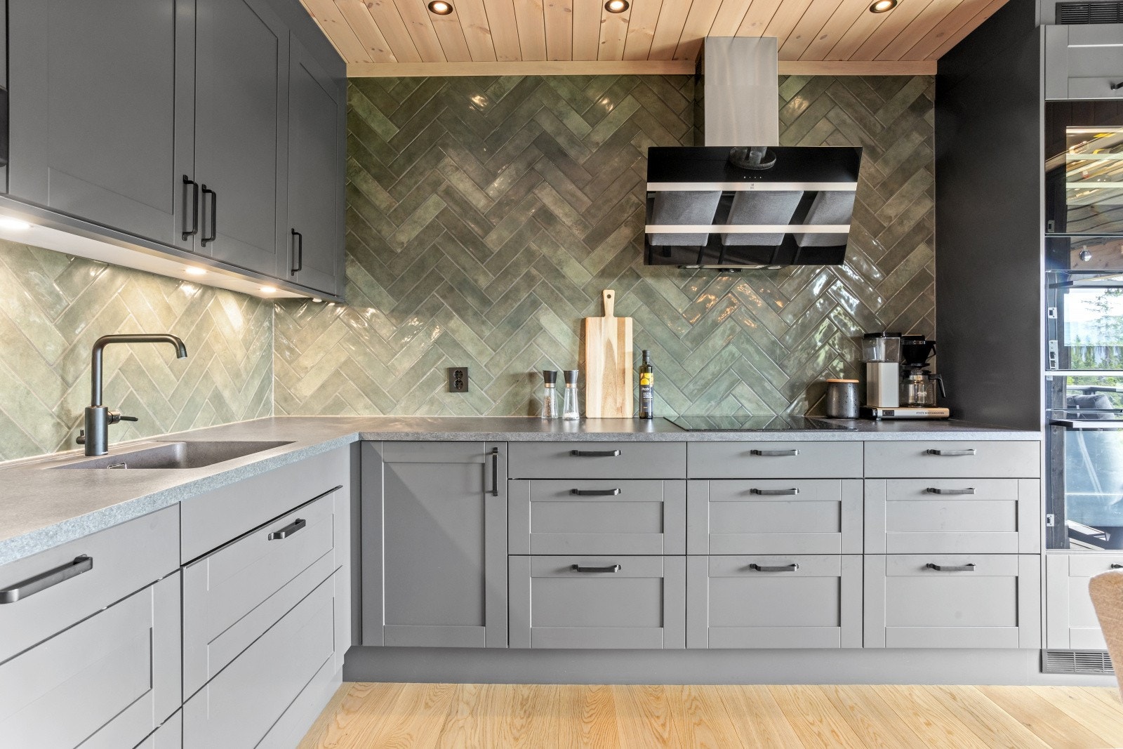 Den ene kortveggen har overskap, mens den andre er holdt åpen - her er hele veggflaten kledd med vakre fiskebeinsfliser i grønntoner som strekker seg helt opp til himlingen. Flisene utgjør et markant og stilfullt blikkfang, og gir rommet karakter og dybde Galleribilde