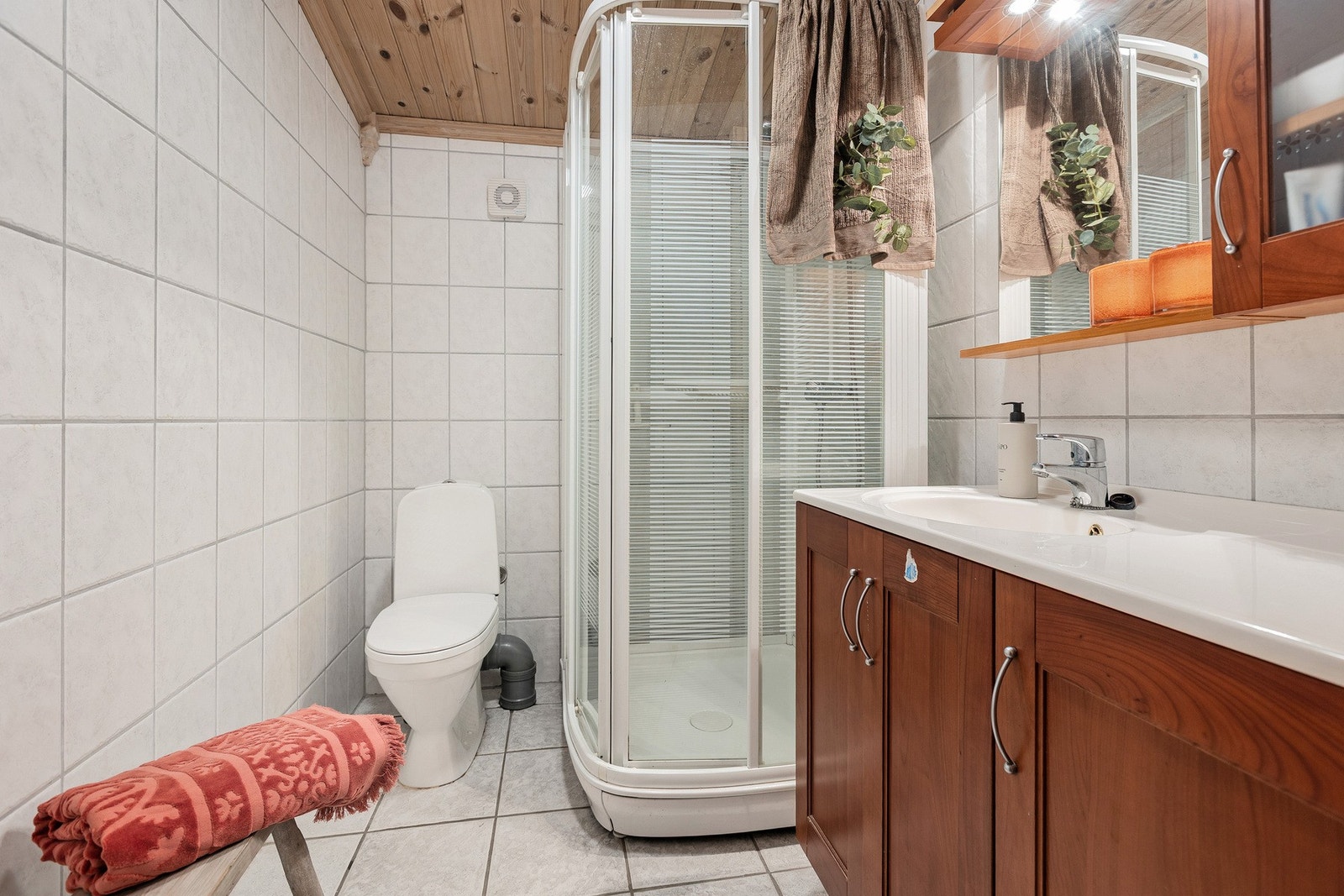 Praktisk og funksjonelt bad med flislagte overflater på gulv og vegger samt panel i himling. Galleribilde