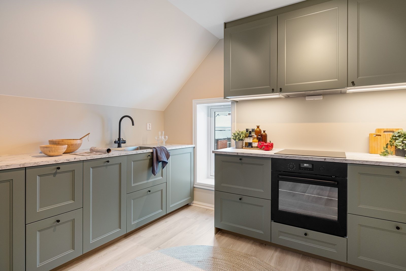 Pent og hyggelig kjøkken med innredning fra IKEA. Innredningen består av over- og underskap med grønne, profilerte fronter. Galleribilde