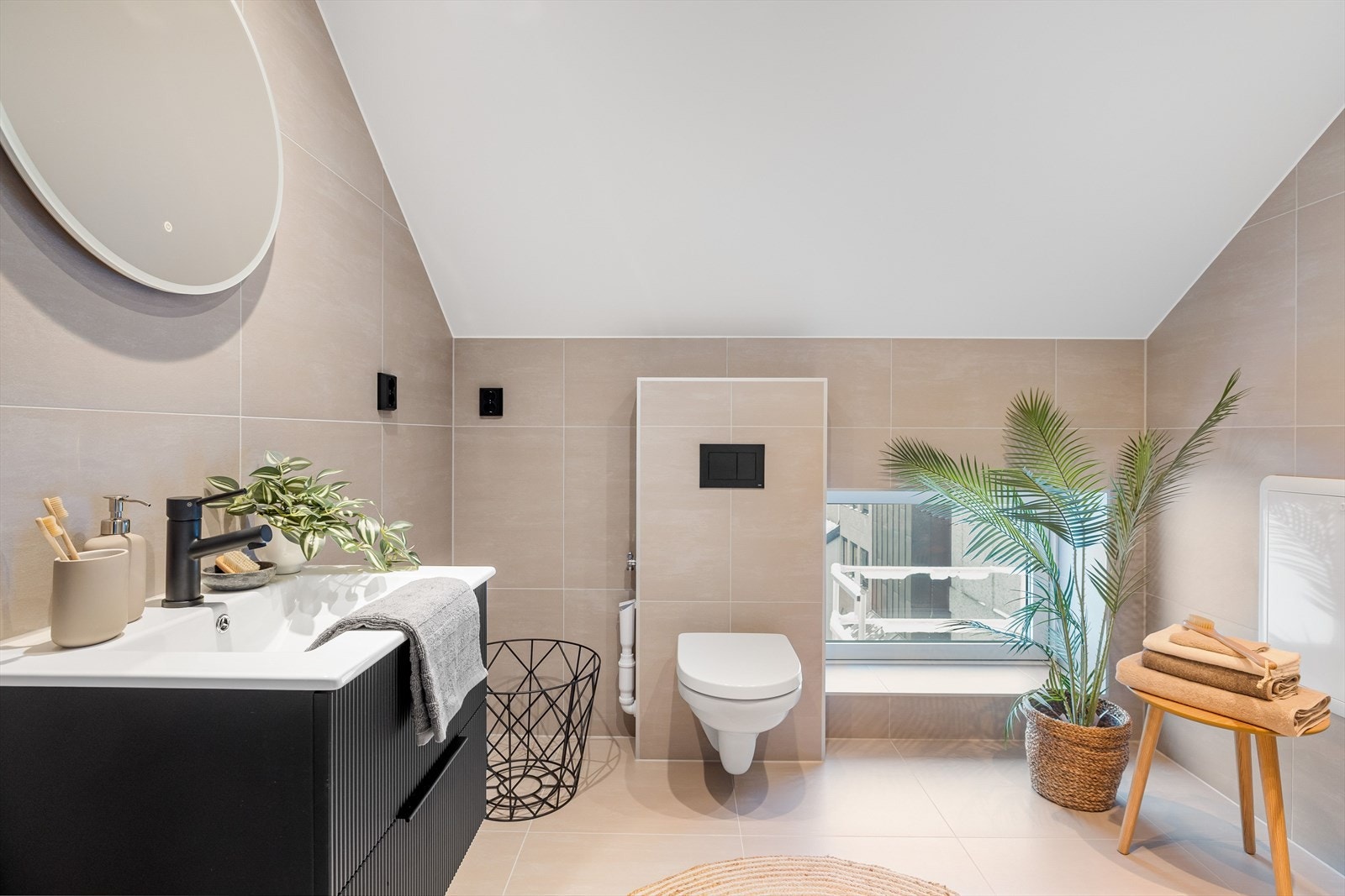 Lekkert, flislagt bad med varmekabler i gulvet. Badet er utstyrt med veggmontert toalett og opplegg for vaskemaskin. Galleribilde