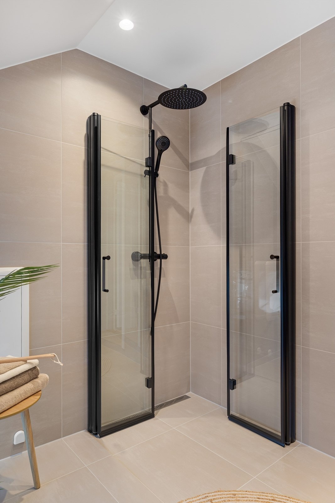 Dusjhjørne med innfellbare dusjdører og vegghengt dujbatteri med regnfall. Galleribilde