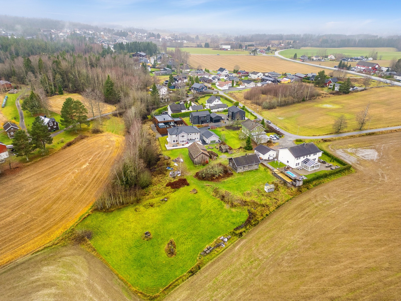 Et område preget av åpne flater, grønne omgivelser og lav bebyggelse. Galleribilde