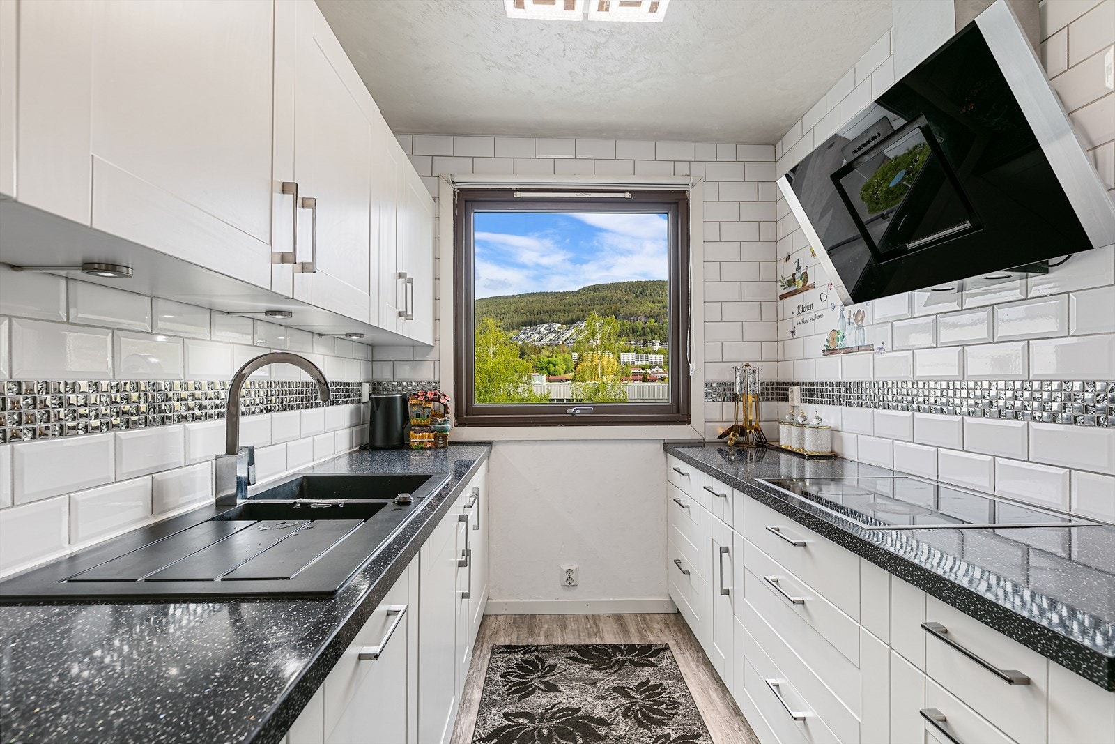 Klassisk og elegant kjøkkeninnredning med hvite profilerte fronter og benkeplate av laminat. Galleribilde