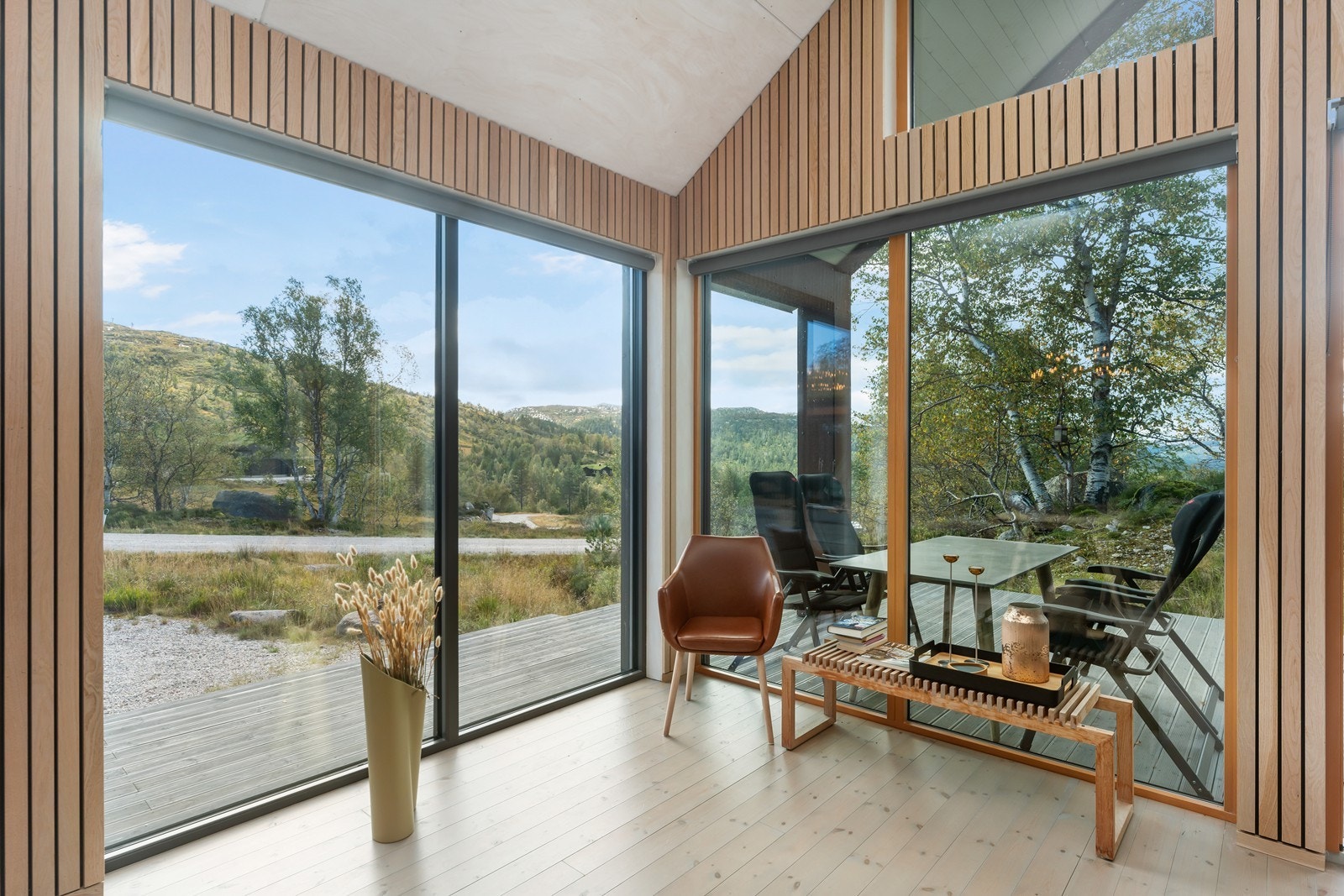 Kombinasjonen av trepanel og store vinduer gir en lun og stilren atmosfære. Galleribilde