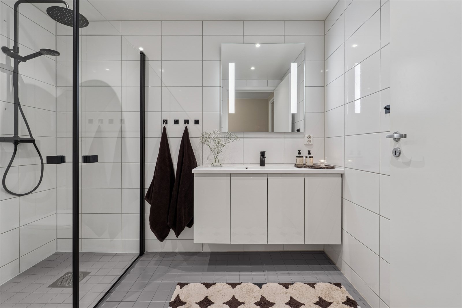 Baderomsinnredning med glatte fronter og speil med integrert belysning. Galleribilde