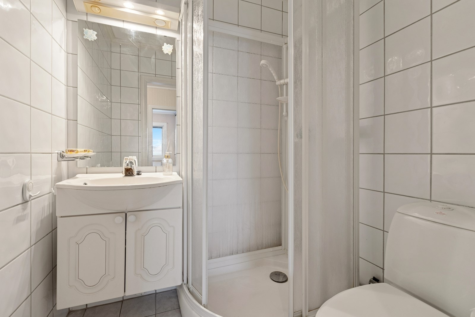 Bad med dusjkabinett, enkel innredning og toalett. Galleribilde