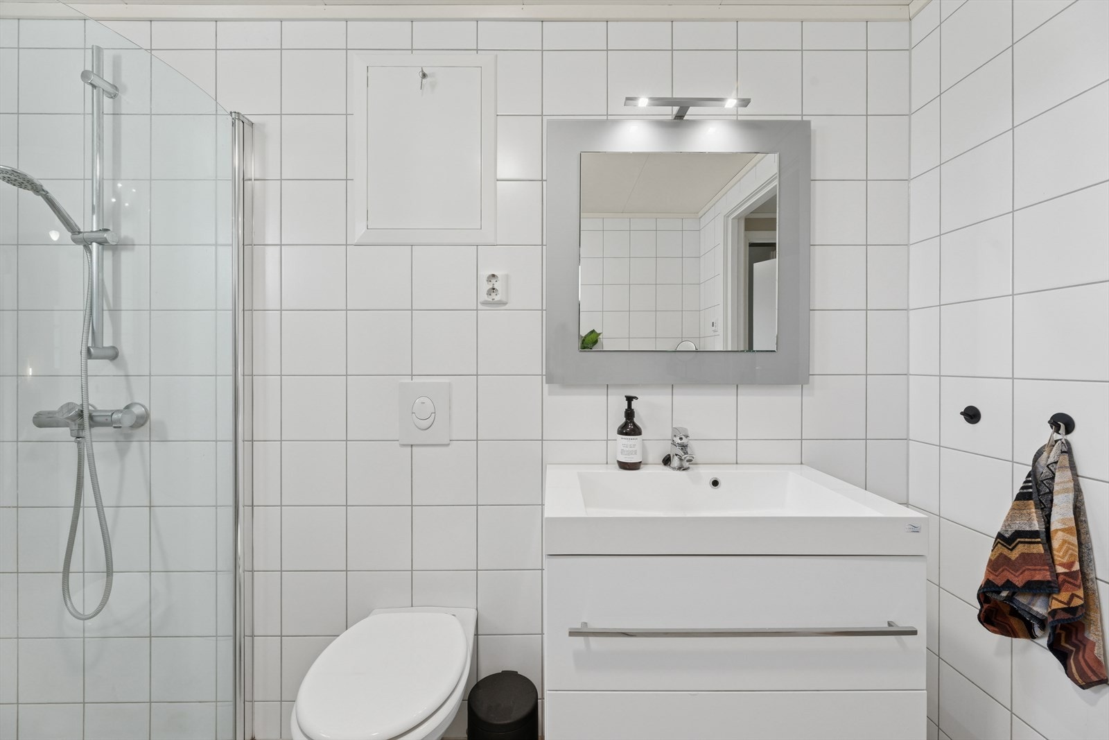 Badet er ellers utstyrt med dusjhjørne, vegghengt toalett og baderomsinnredning med nedfelt servant. I tillegg har man opplegg for vaskemaskin og plass til tørketrommel. Galleribilde