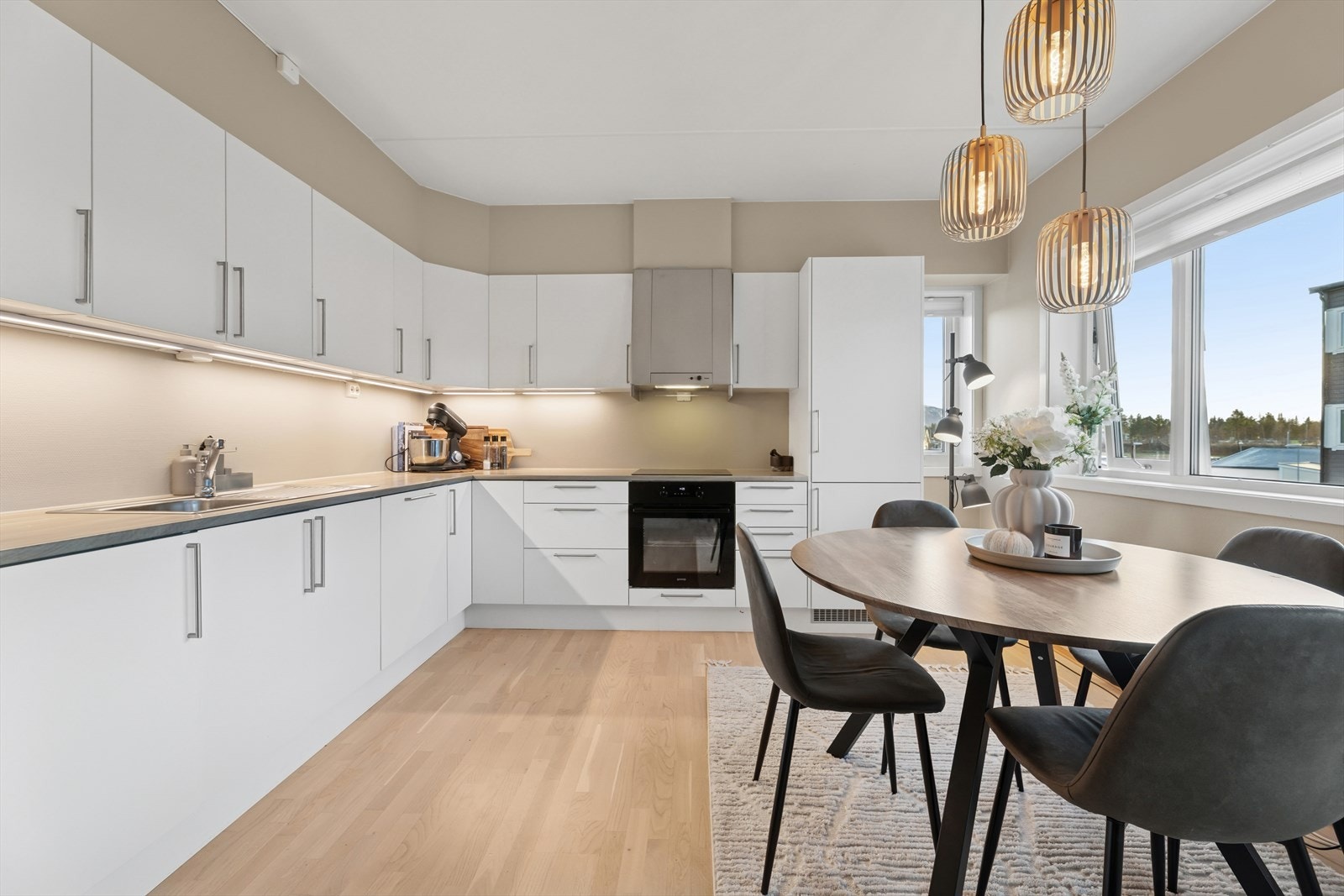 Kjøkkenet er stilrent og moderne med hvite, slette fronter og grå benkeplate i laminat. Et stort og godt kjøkken hvor man har rikelig med skap- og skuffeplass, samt gode arbeidsflater på benk. Galleribilde