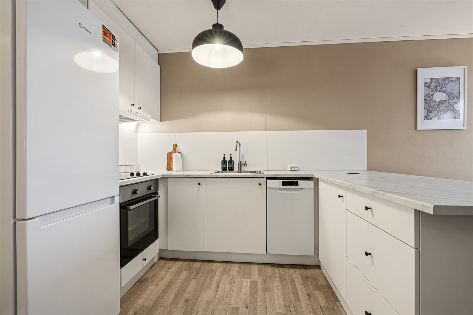 Praktisk kjøkken i åpen løsning med godt med benkeplass og integrerte hvitevarer som koketopp, stekeovn og oppvaskmaskin. Her får du en funksjonell og trivelig arbeidsplass. Galleribilde