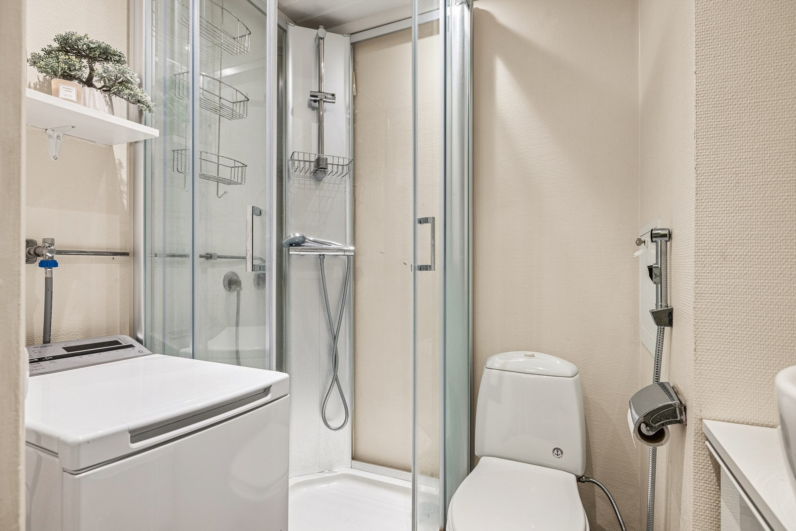 Praktisk bad med opplegg for vaskemaskin, dusjkabinett, toalett og servant. Galleribilde