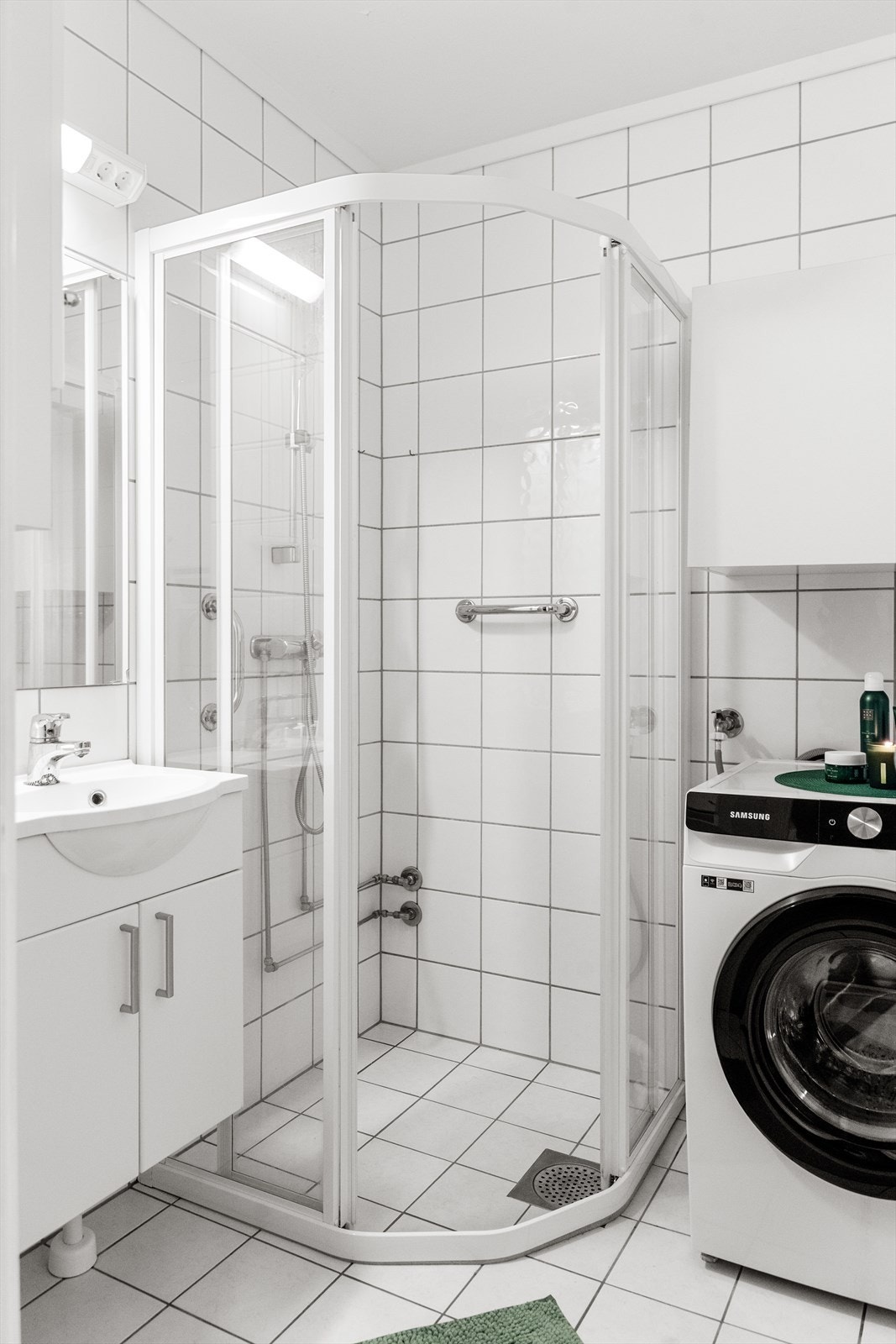 Pent flislagt bad med varmekabler i gulv. Badet er utstyrt med heldekkende servant med underskap, overskap, speil, lys, dusjnisje og opplegg til vaskemaskin. Galleribilde