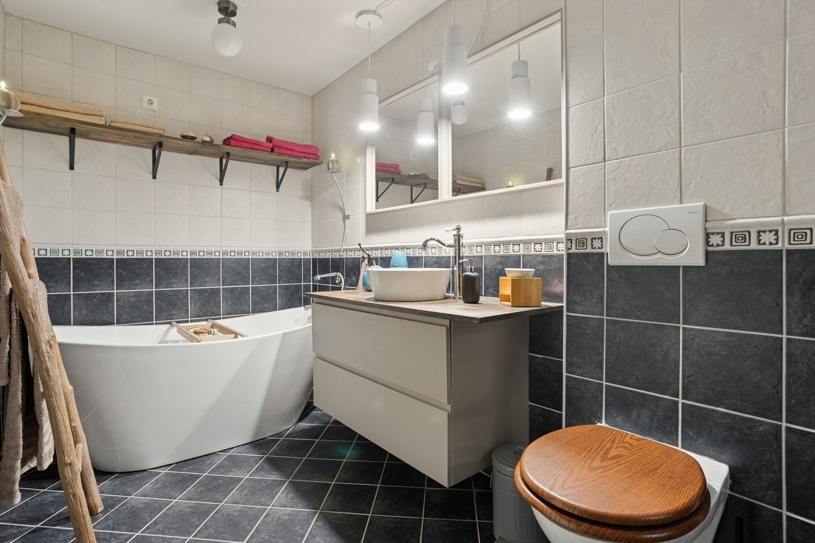 Innredningen består av et veggmontert toalett, en toppmontert servant med underskap, dusj med glassvegg og et badekar. Galleribilde