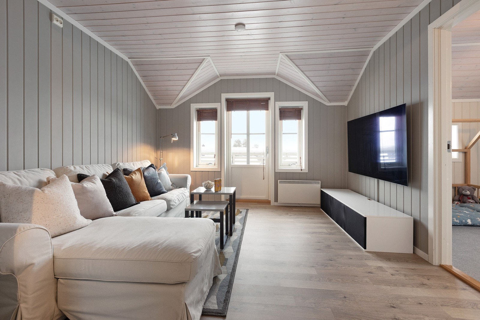 Hyggelig tv-stue med utgang til balkong fra her. Malt panel på vegg og behandlet himling og laminat gulv. Galleribilde