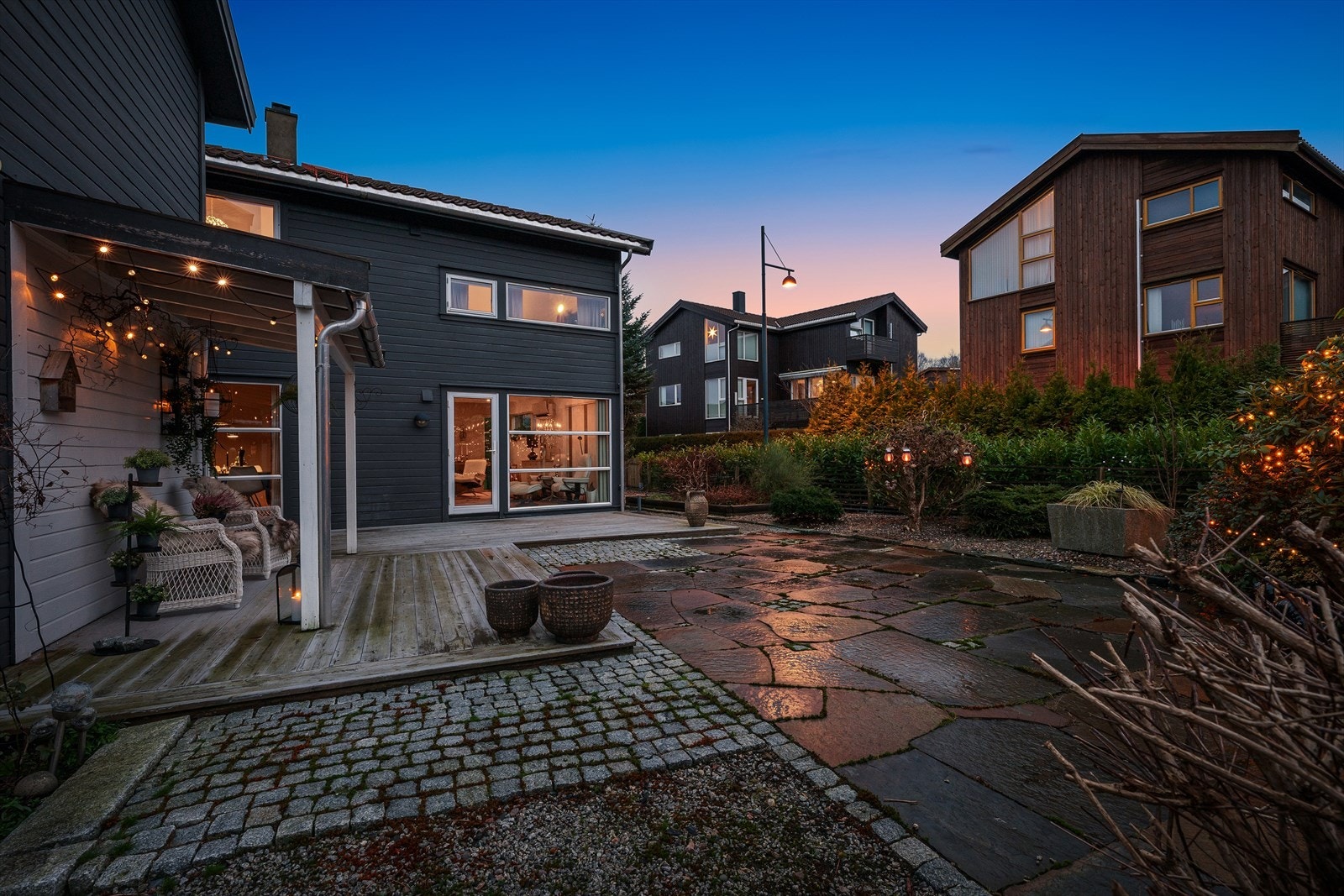 Brostein, skiferheller, og treterrasse. Dansk elvestein og pen, lettstelt beplantning. Galleribilde