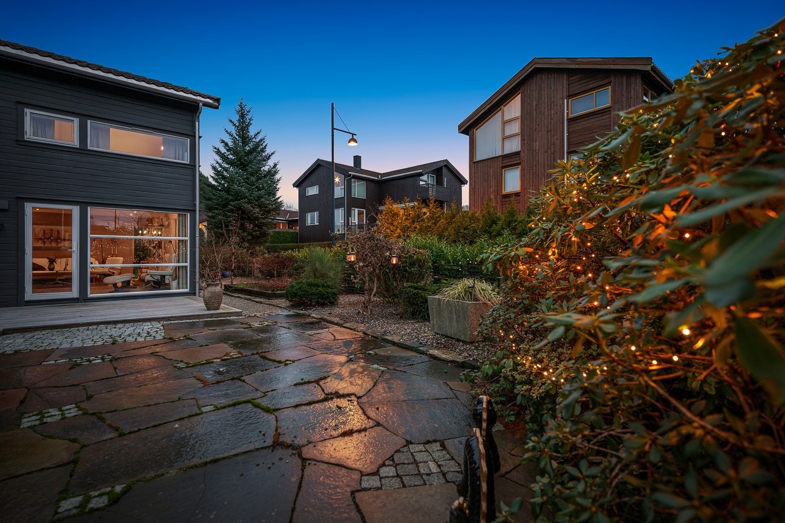 Brostein, skiferheller, og treterrasse. Dansk elvestein og pen, lettstelt beplantning. Galleribilde