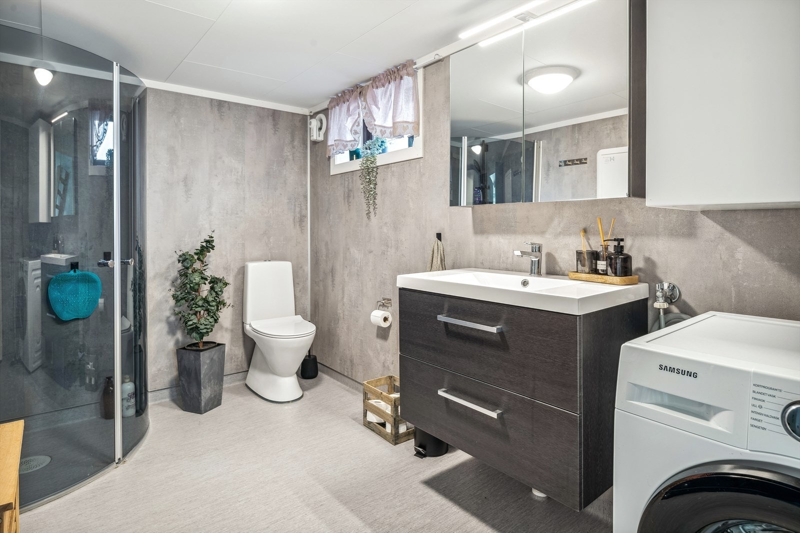 Stort og moderne bad/vaskerom som ble pusset opp i 2021. Baderommet har våtromsbelegg på gulv med gulvvarme, våtromsplater på veggene, et lite vindu og elektrisk styrt vifte. Galleribilde