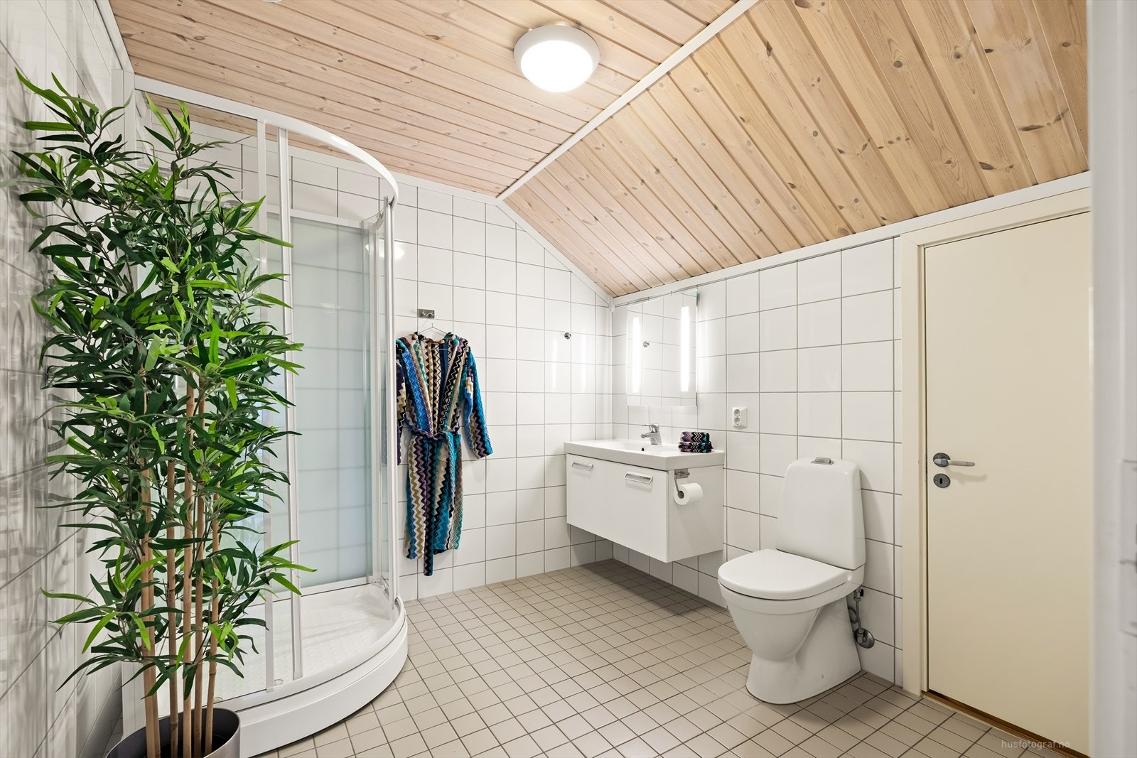 Pent flislagt bad med gulvvarme på loftsetasjen. Badet utstyrt med baderomsinnredning med heldekkende servant, speil med belysning, toalett og dusjkabinett. Galleribilde