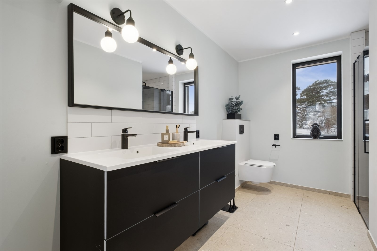 Pent bad i 2. etasje som har flislagt gulv med vannbåren gulvvarme. Badet er utstyrt med vegghengt toalett, innredning med glatte fronter og heldekkende servant med to soner, samt speil med lamper over. Galleribilde