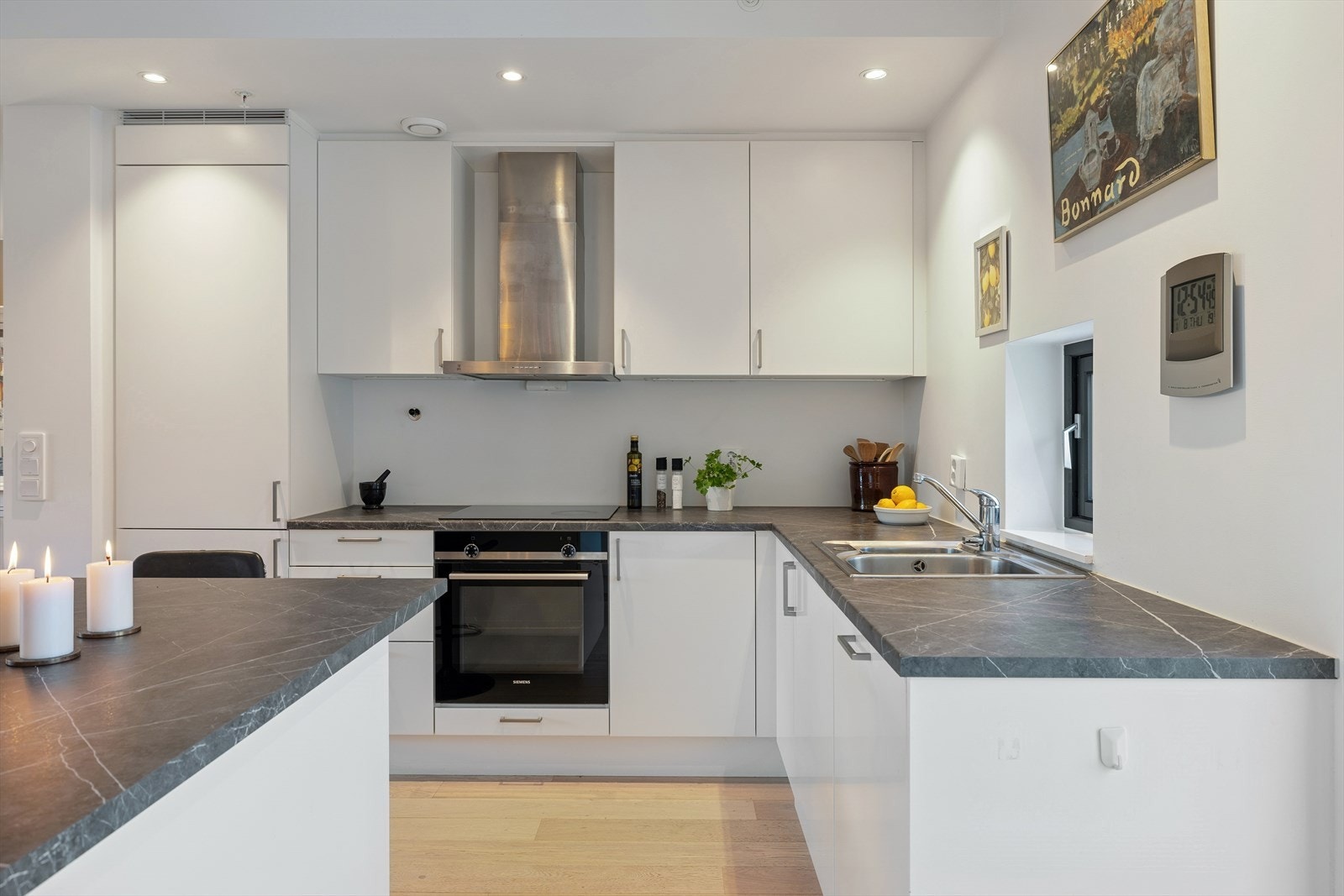 Moderne og stilrent kjøkken fra 2022, med hvite, slette fronter og mørk laminat benkeplate. En tidløs og elegant fargekombinasjon. Galleribilde