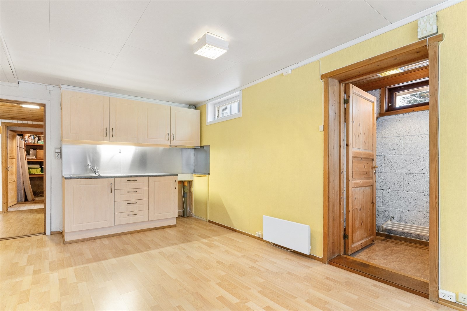 Enkel kjøkkeninnredning med slette dører. Kjøkkenet har plass til kjøleskap/frys på gulv vegg, og komfyr i innredningen. Det er laminat benkeplate. Det er kjøkkenventilator med avtrekk ut. Egen inngangsdør ut til hage. Galleribilde