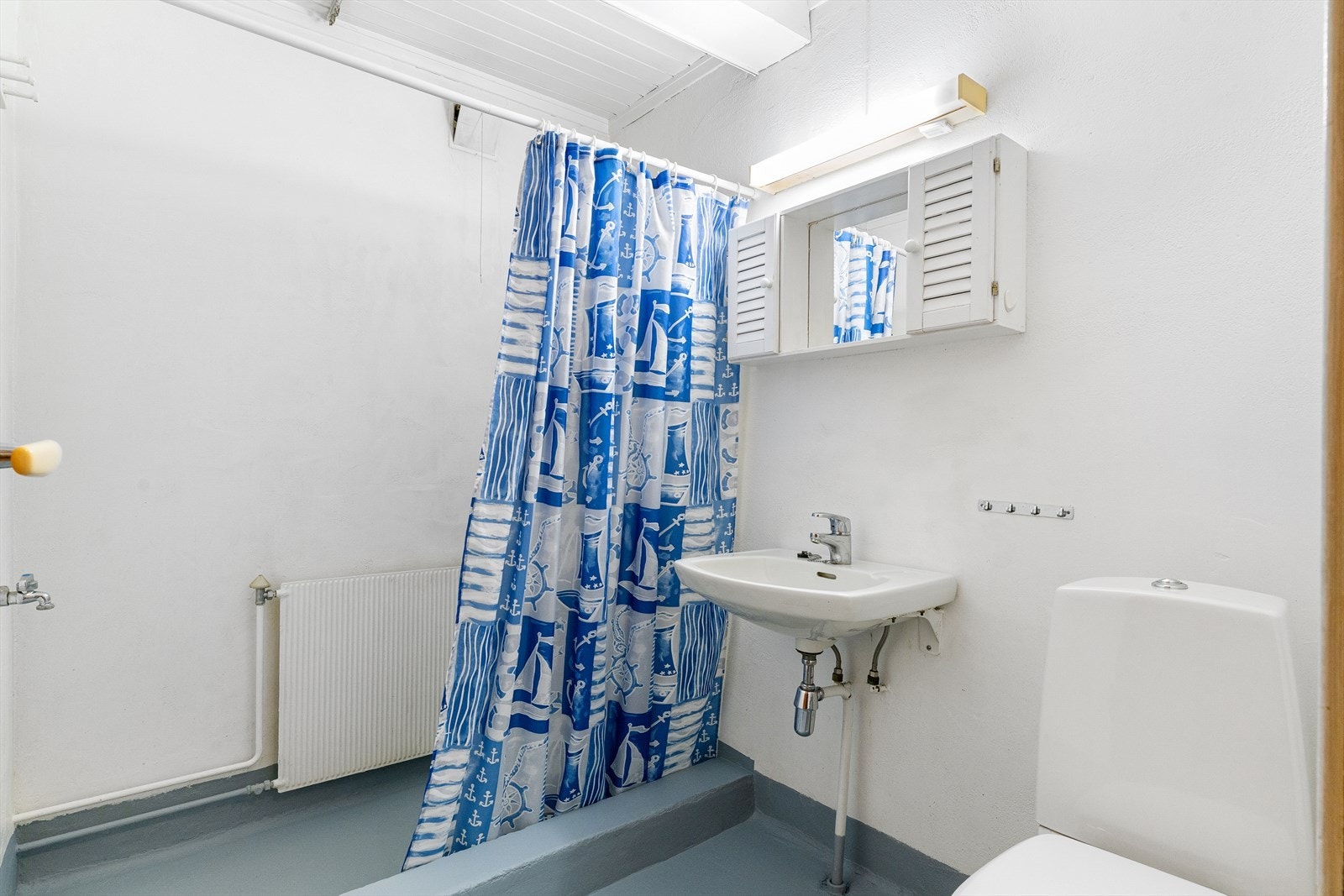 Badet er i daglig bruk, men vurderes å behøve modernisering for å stå til dagens standarder. Badet er tilhørende hybeldelen. Dusjnisje bak forheng, servant og toalett.. Galleribilde