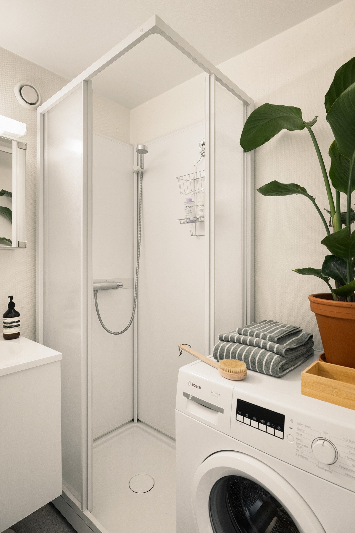 Badet har veggmontert toalett, dusjkabinett med skyvedører samt opplegg for vaskemaskin og tørketrommel. Galleribilde