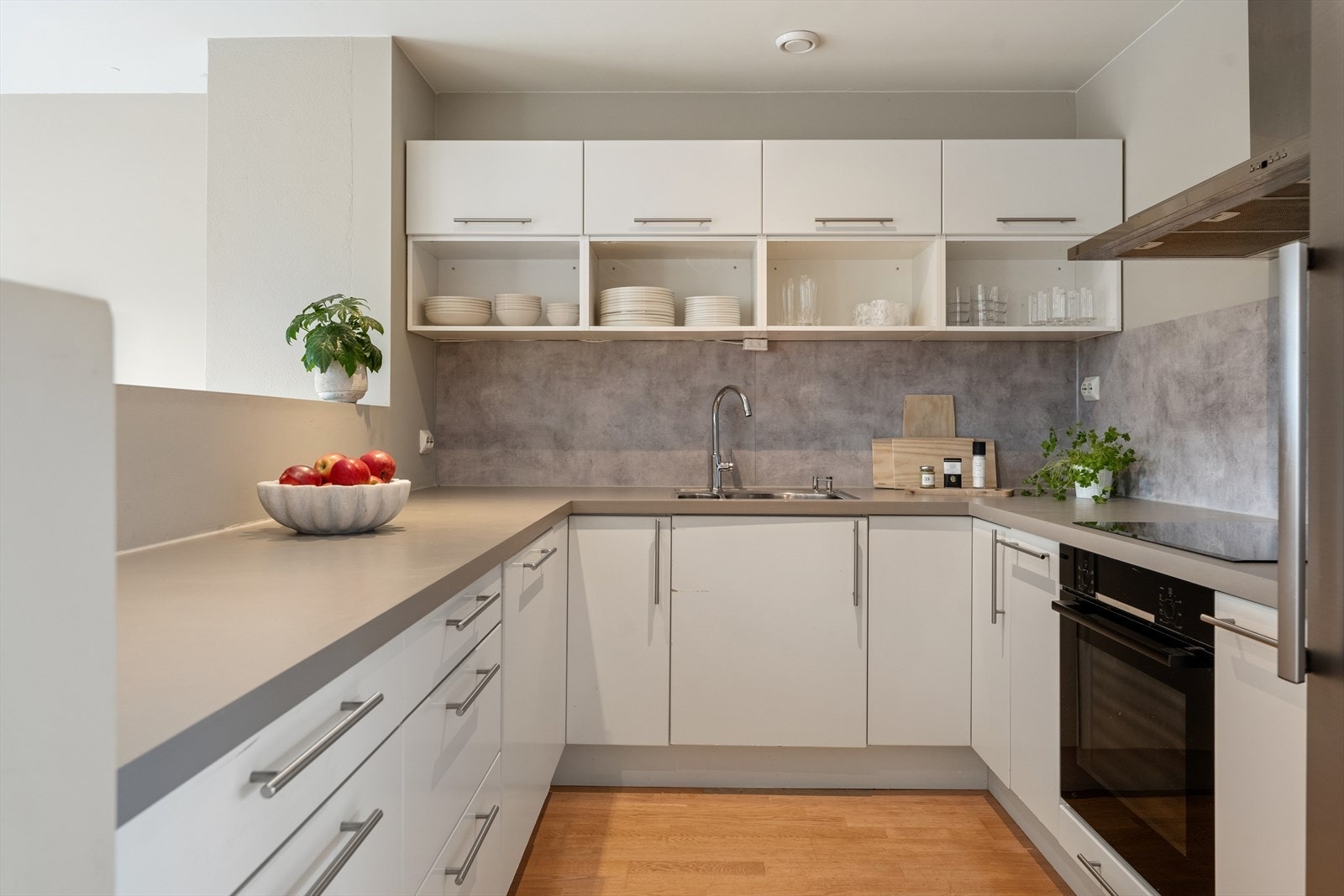 Kjøkkenet har innredning med slette fronter og en benkeplate i laminat. Mellom benkeplaten og veggen er det montert plater. Galleribilde