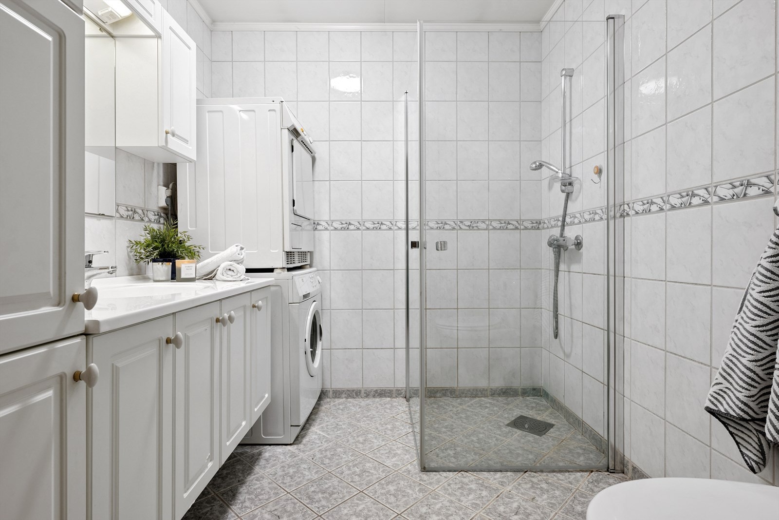 Moderne, flislagt bad med gulvvarme, dusjvegger og opplegg for vaskemaskin. Galleribilde