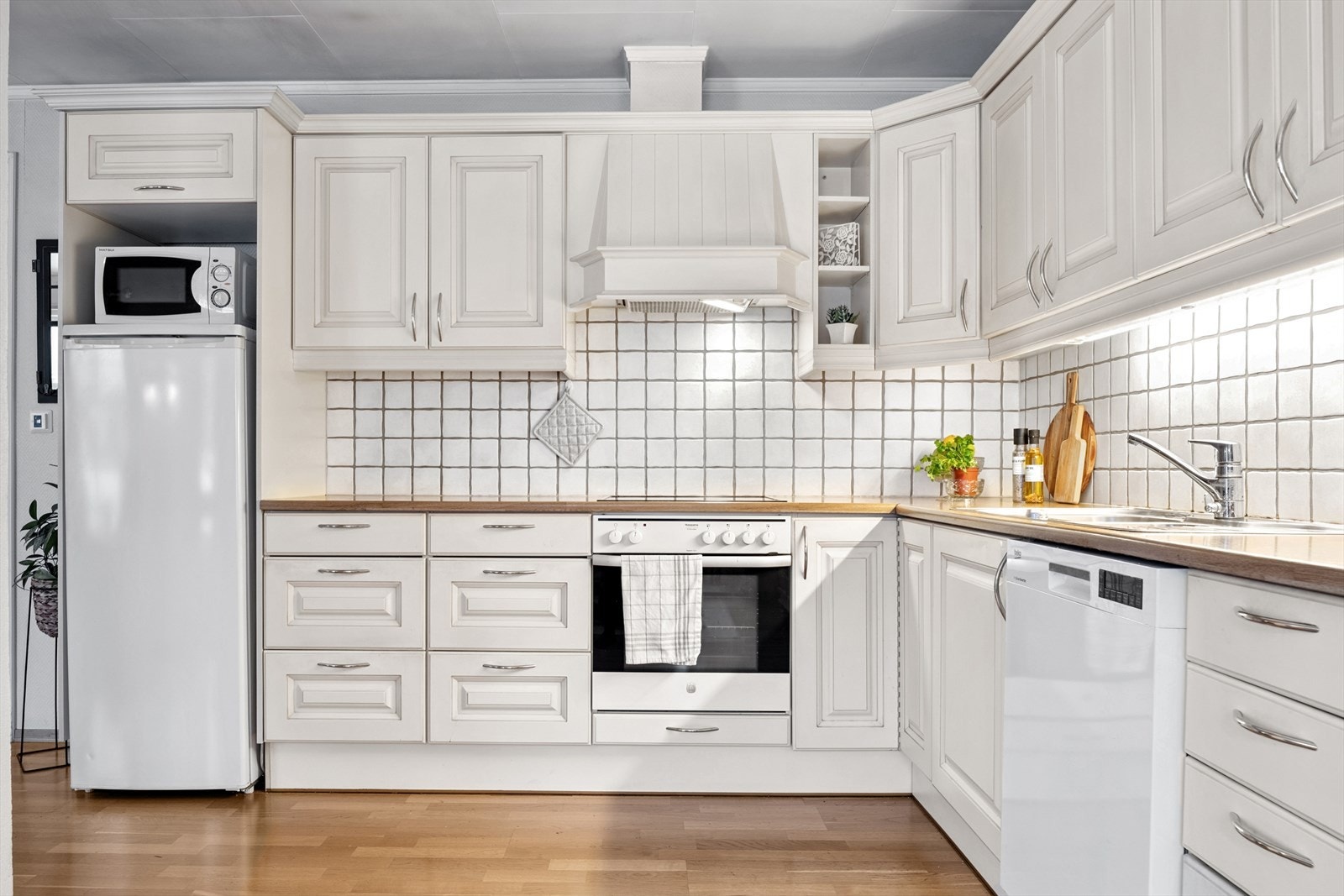 Kjøkkeninnredning med profilerte fronter, laminert benkeplate og integrert komfyr og koketopp. Galleribilde