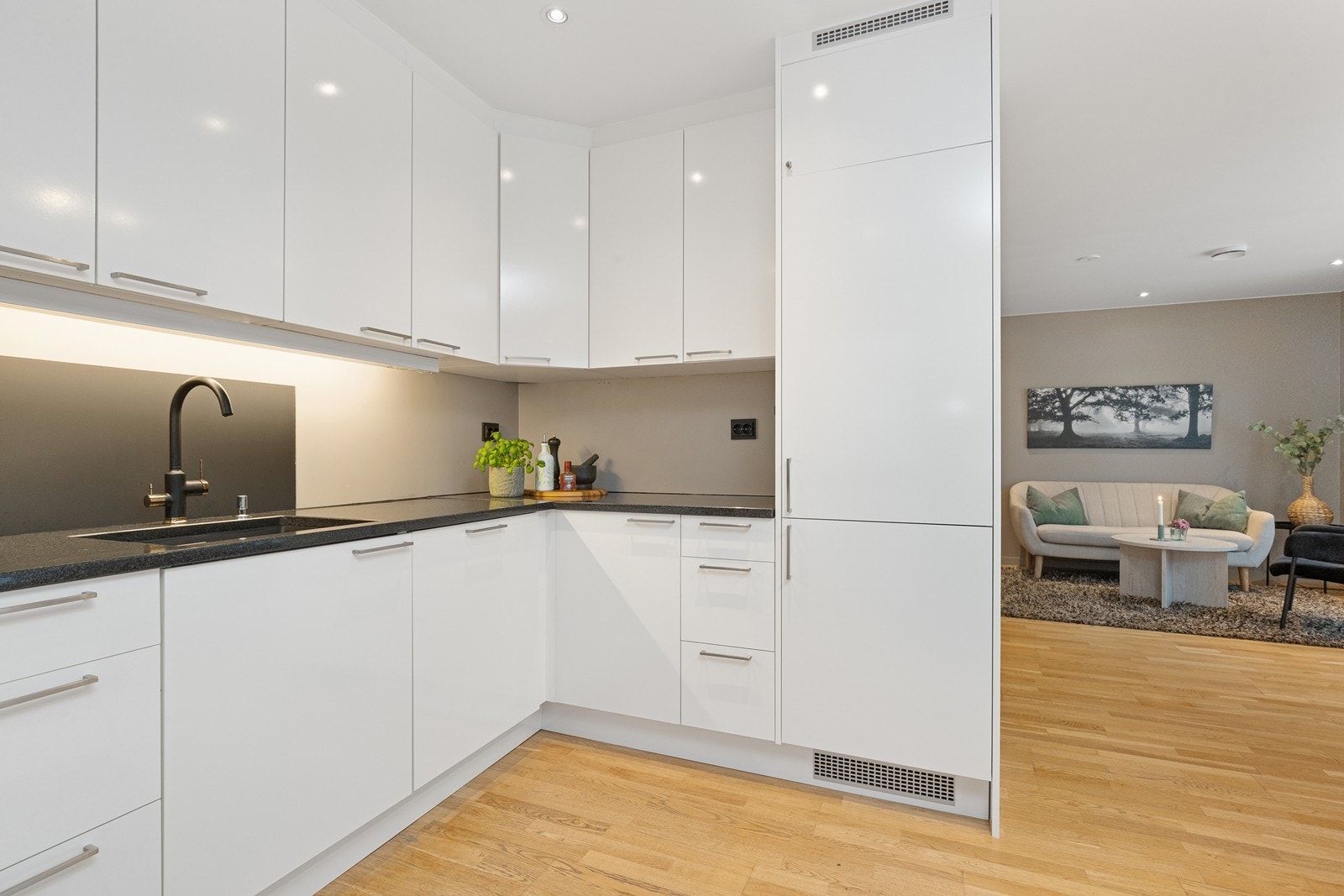 Kjøkkeninnredning med glatte, hvite fronter og rikelig med skap- og benkeplass. Galleribilde