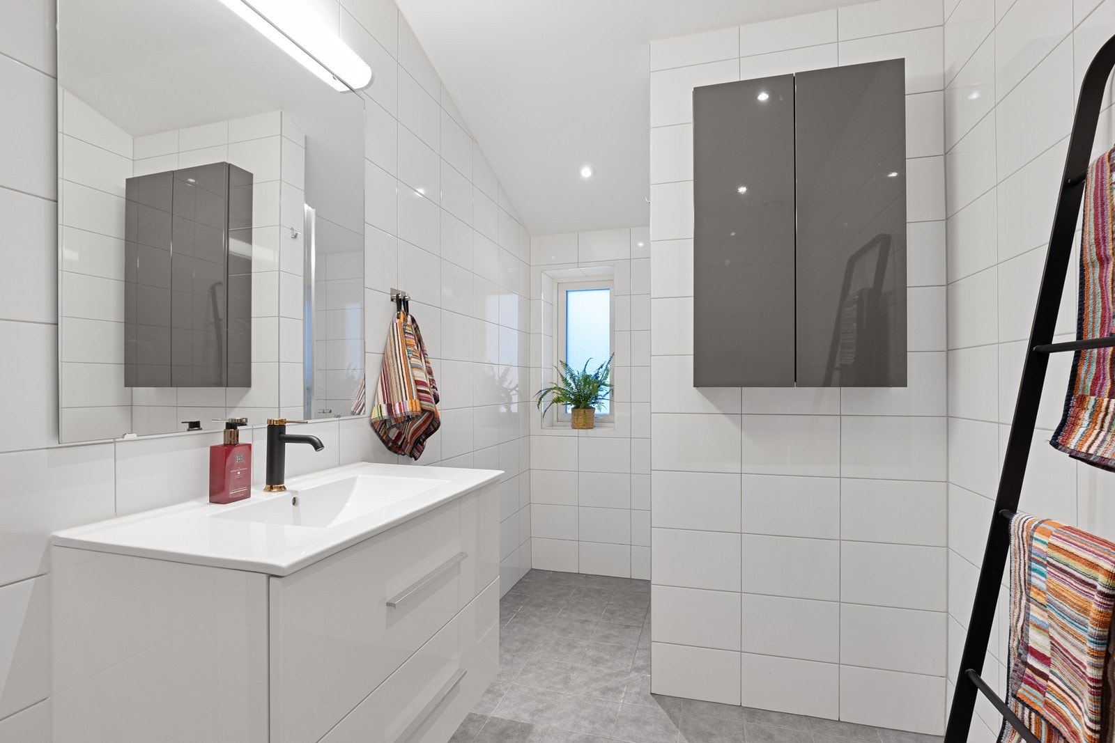 Badet i 2. etasje er helfliset og utstyrt med servantmøbel og overskap Galleribilde