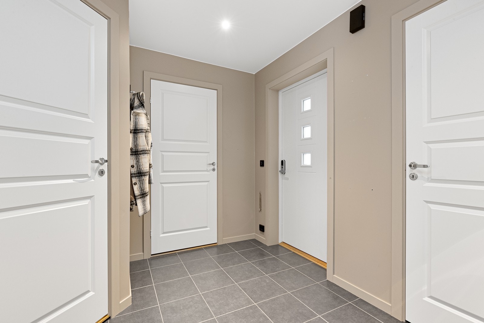 Velkommen inn i en romslig entré med praktiske fliser på gulvet. Galleribilde