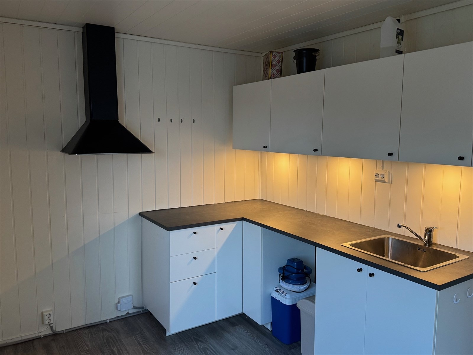 Kjøkkenet har nyere innredning fra 2022 med hvite glatte fronter og en laminat benkeplate, samt kjøkkenventilator med avtrekk ut. Galleribilde