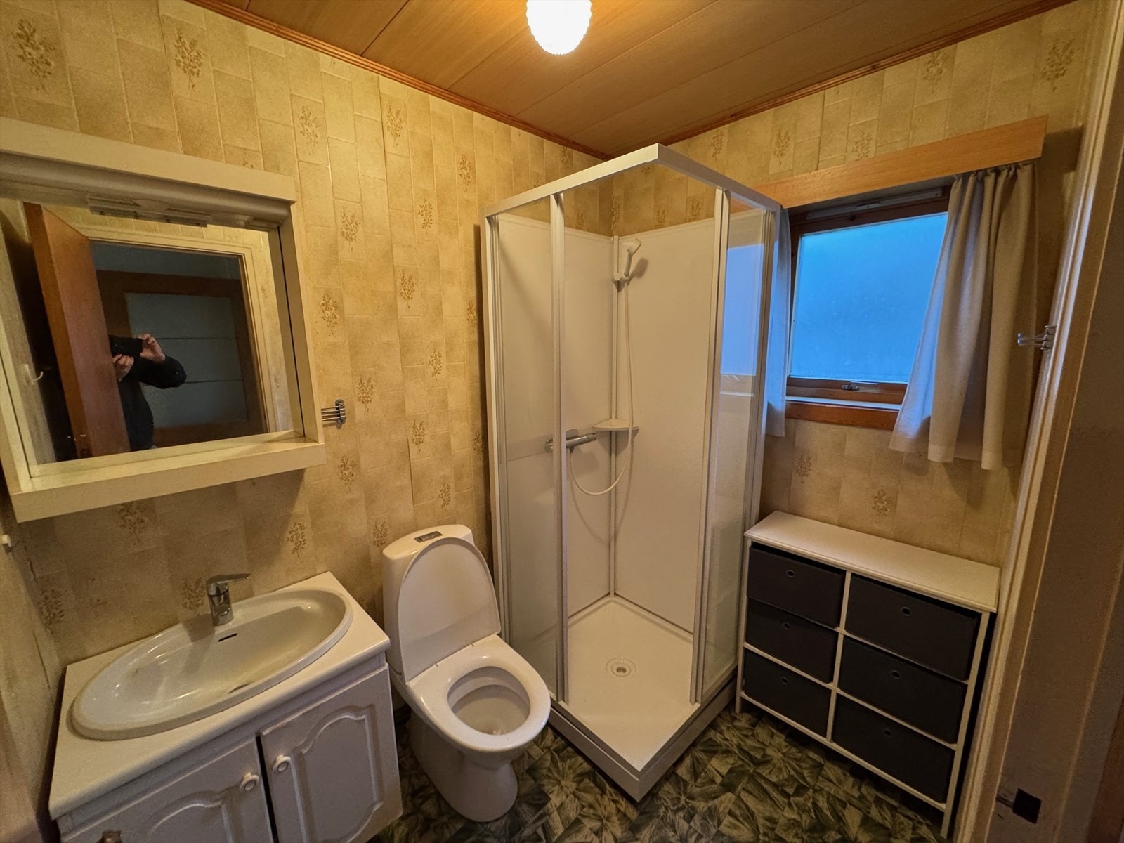 Badet er utstyrt med dusjkabinett, servant og toalett, men har eldre belegg og krever oppgradering. Galleribilde