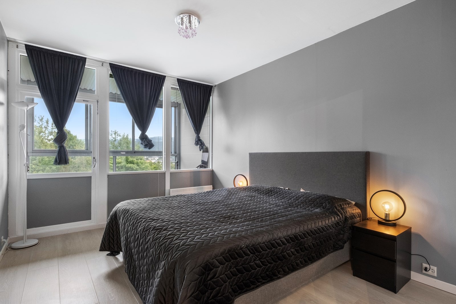 Store vinduer og utgang til balkong gir godt med naturlig lys og utsikt mot grøntområder. Galleribilde