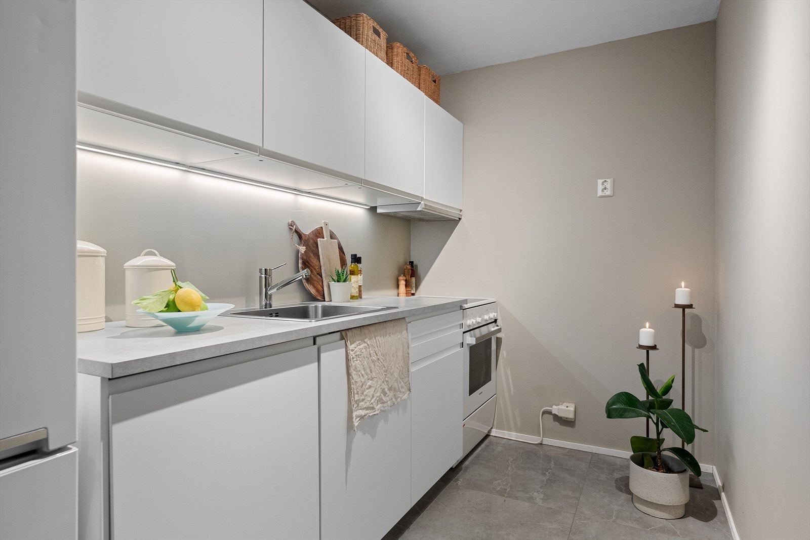 Kjøkkeninnredning med glatte fronter, laminat benkeplate med nedfelt kum i rustfritt stål. Galleribilde