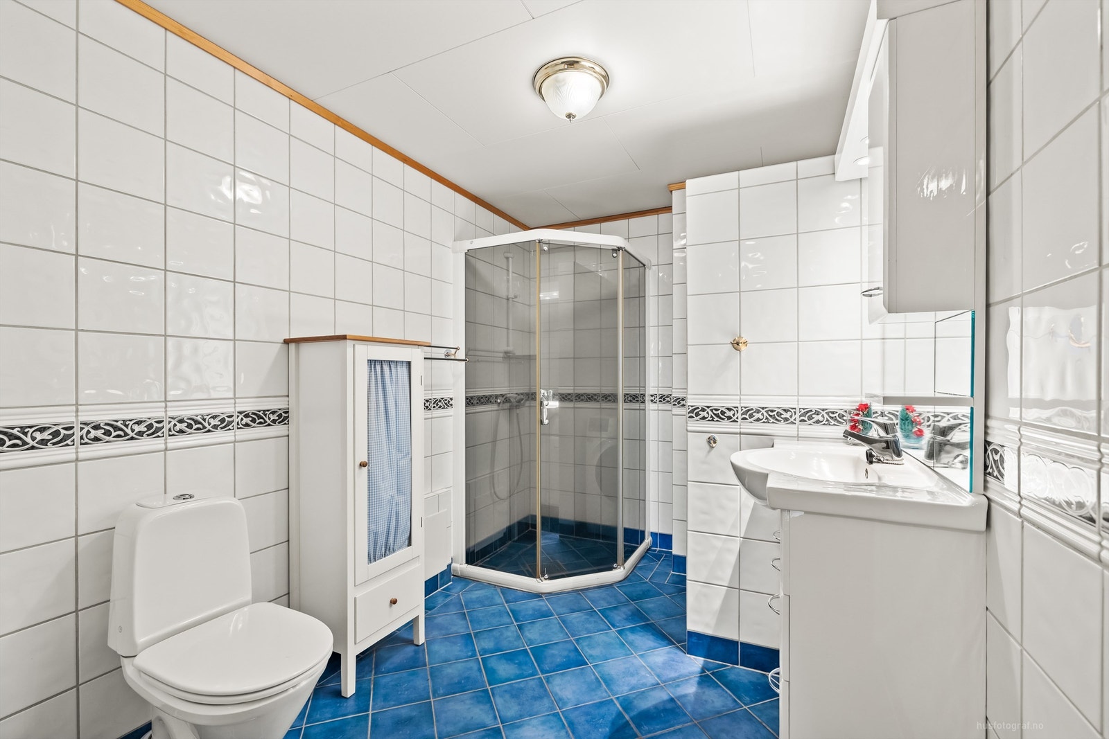 Flislagt bad/vaskerom med dusjhjørne og gulvstående toalett Galleribilde