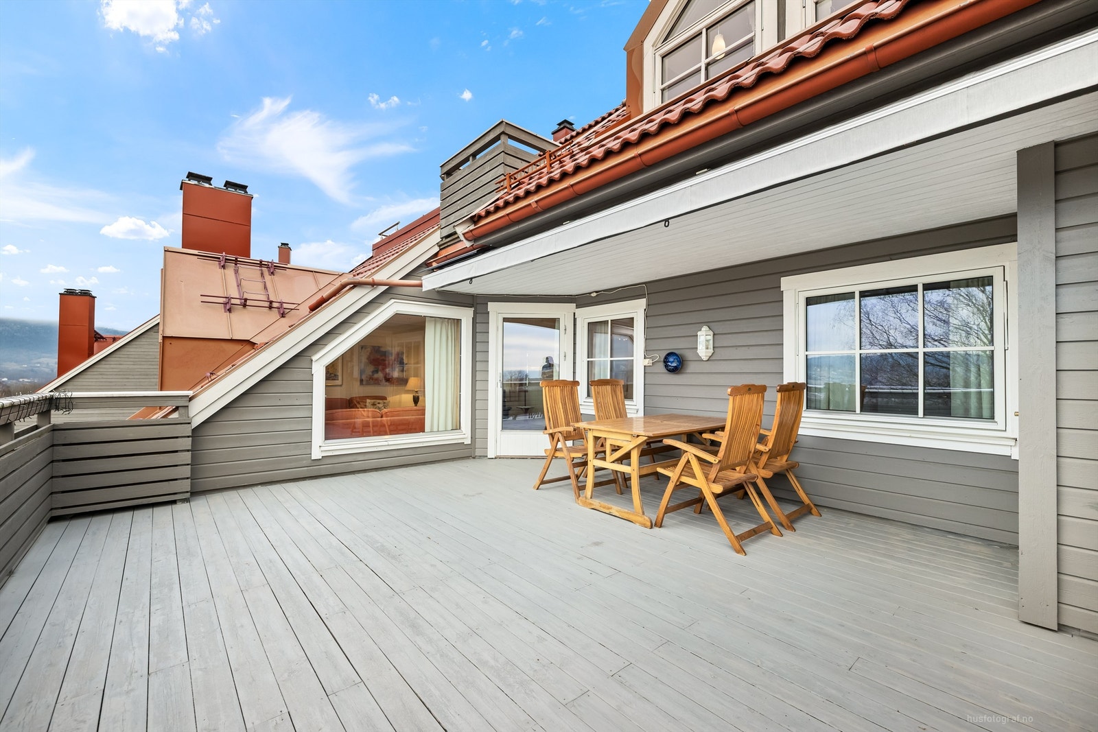 Terrasse med dekke av trebord, utvendig belysning, strømuttak og markise Galleribilde
