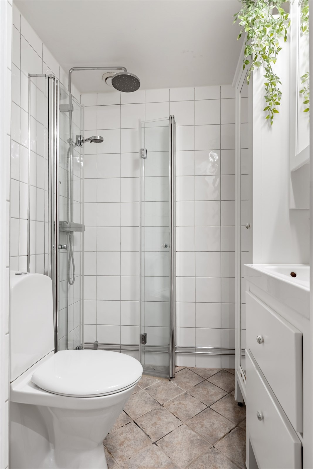 Flislagt baderom med varmekabler, utstyrt med hånd og regndusj med innfellbare dører i herdet glass, toalett og servant med underskap. Galleribilde