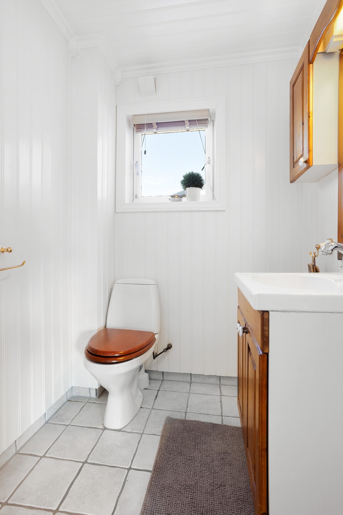 WC-rom med gulvmontert toalett og enkel baderomsinnredning, flislagt gulv Galleribilde