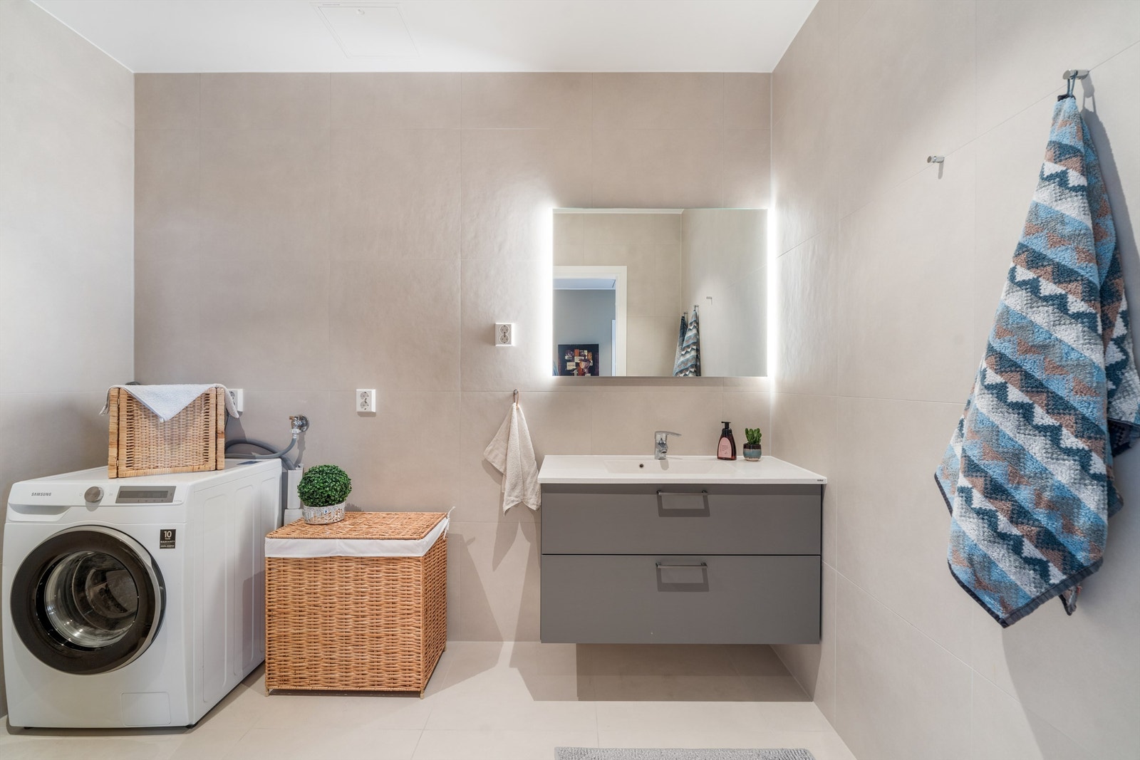 Leiligheten har to stilrene og helflisete bad med innredning fra den anerkjente danske leverandøren HTH. Dette badet er utstyrt med dusj sone, vegghengt toalett, vegghengt servantinnredning og opplegg for vaskemaskin. Galleribilde