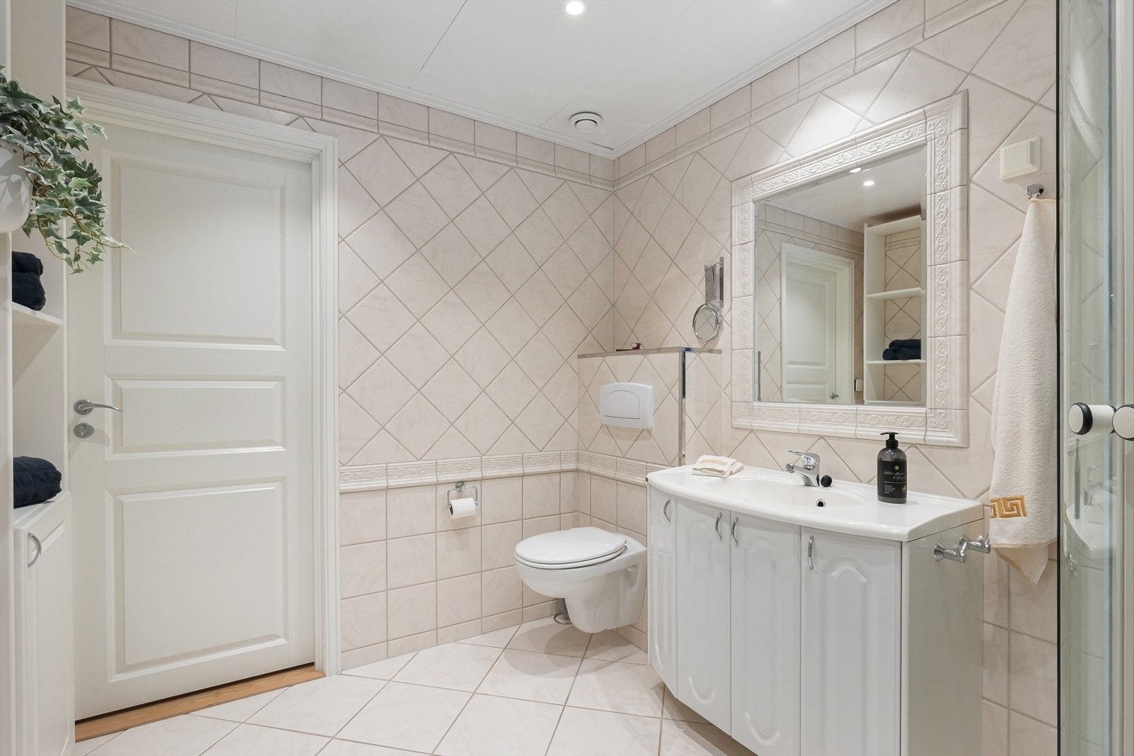 Badet er utstyrt med vegghengt toalett med innbygget sisterne, servantinnredning og dusjkabinett Galleribilde